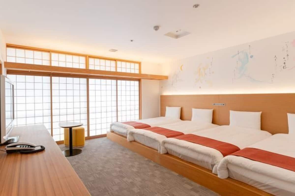 A hotel room with a large window, a bed, a desk, and a small table.