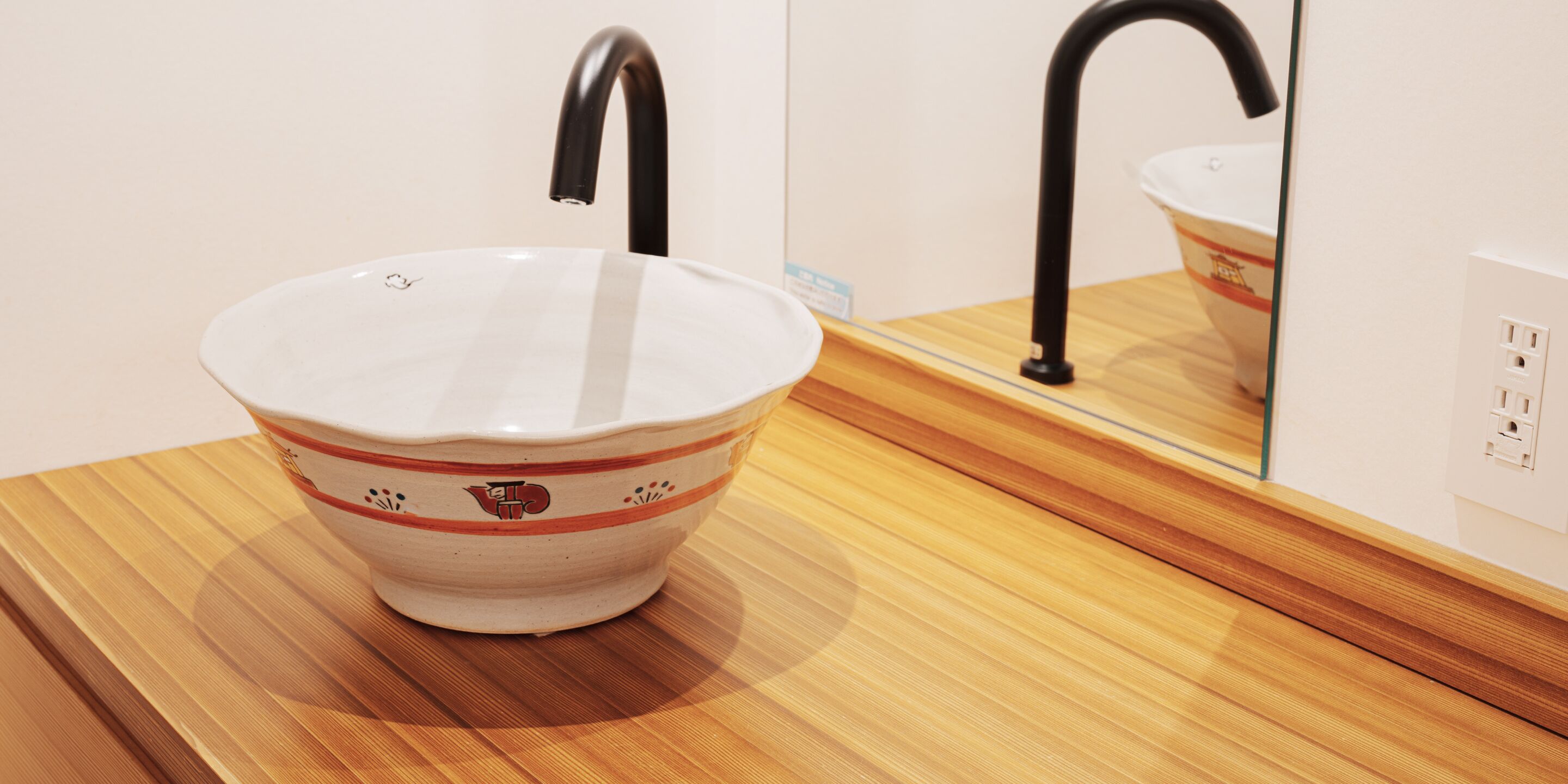 A bathroom sink with a mirror and a wooden countertop.