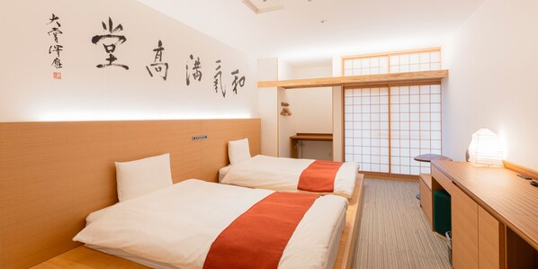 Habitación de hotel con dos camas, un escritorio y un panel corredero estilo shoji.