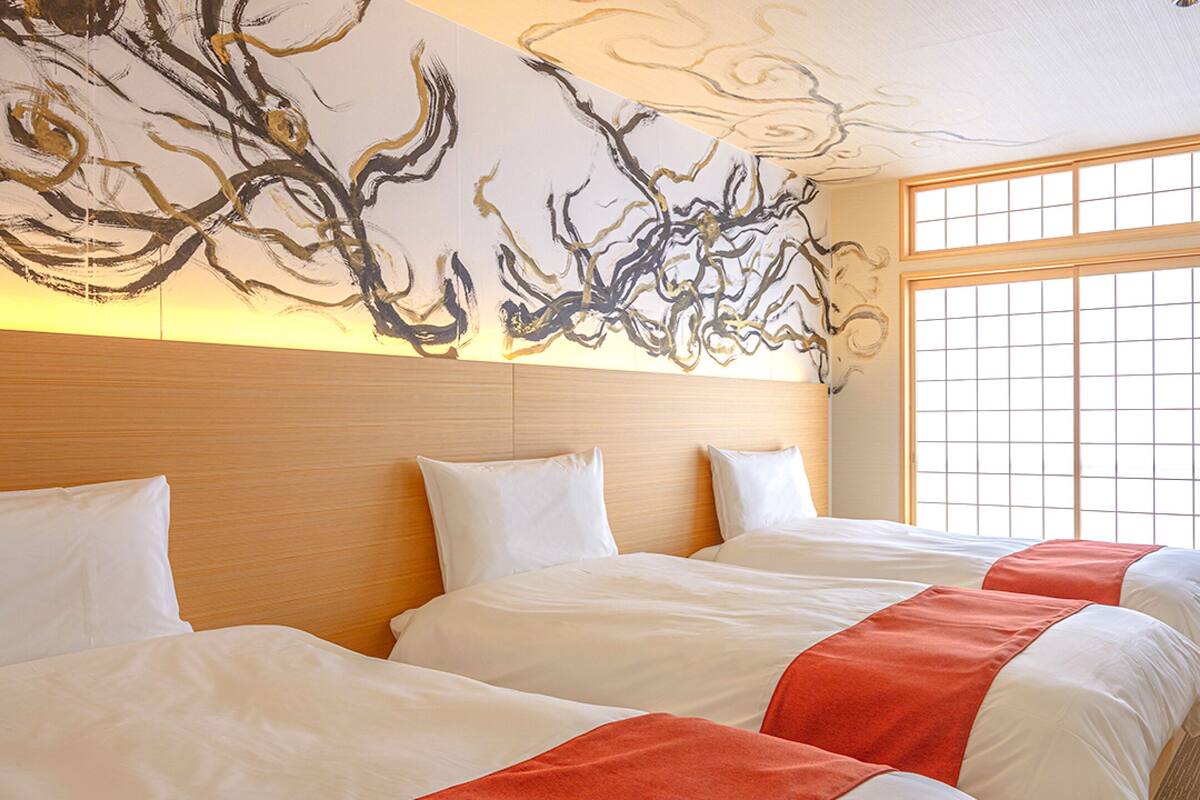 A hotel room with two beds, a large window with a view, and a modern abstract wall art piece.