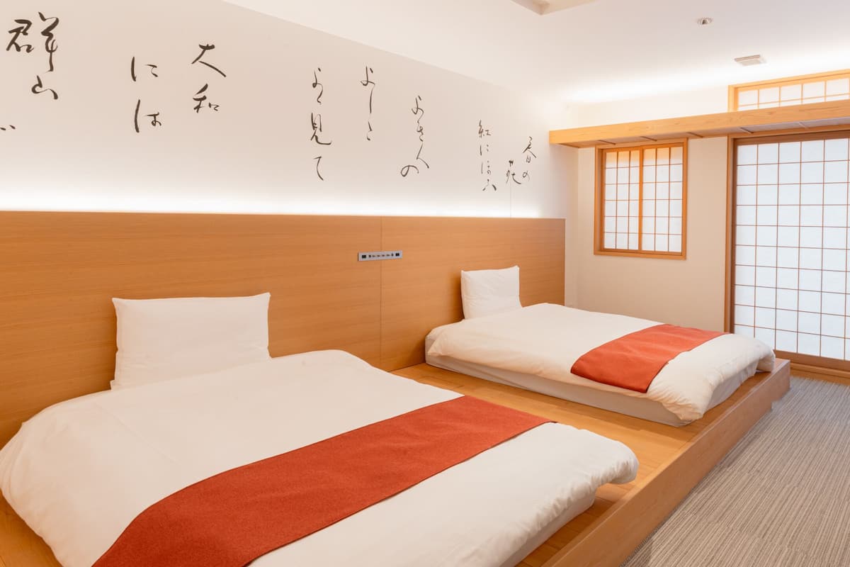A hotel room with two beds, a small table, and a sliding shoji screen.