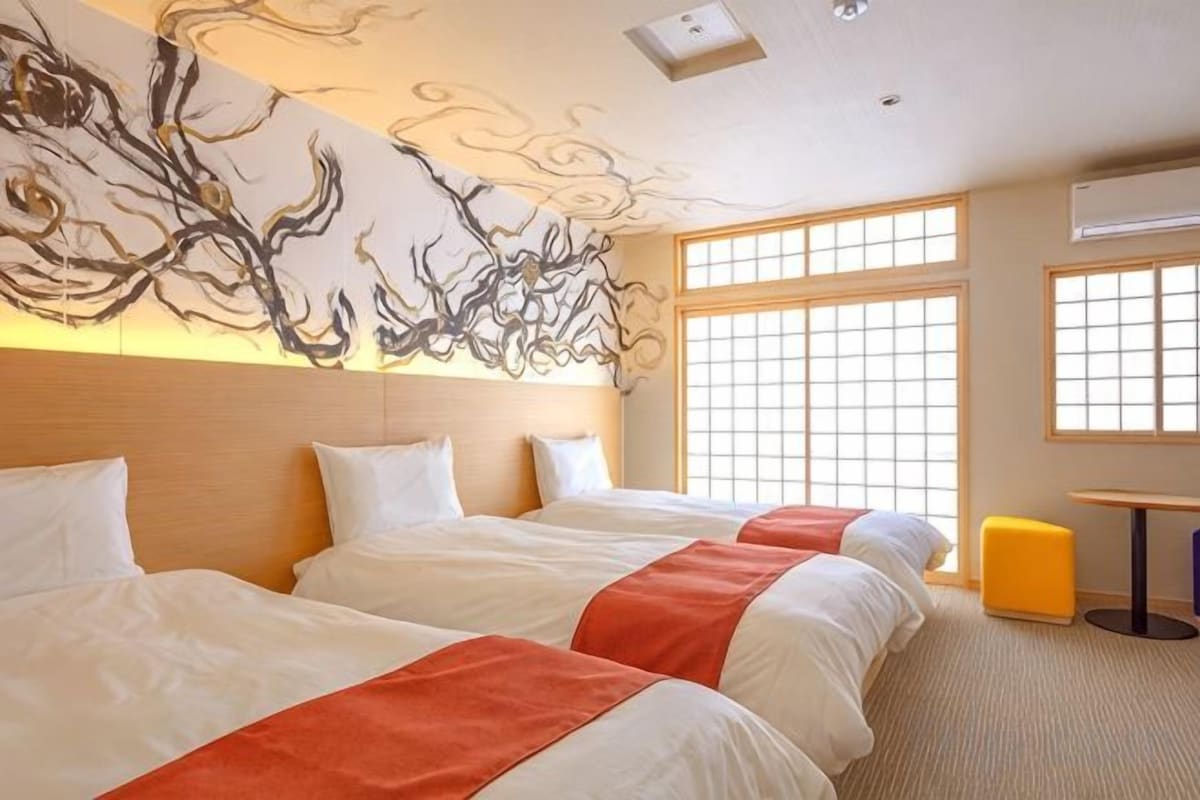 Habitación de hotel con dos camas, un ventanal grande y una obra de arte en la pared.