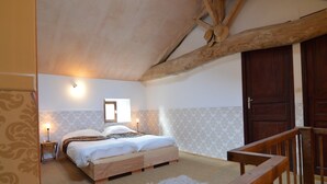 Un dormitorio con una cama de madera, una mesita de noche pequeña con una lámpara, una ventana y una puerta de madera.