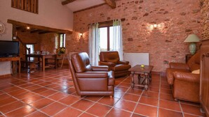 Una sala de estar rústica con paredes de piedra, vigas de madera y baldosas de terracota.