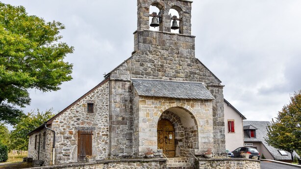 Una chiesa in pietra con un campanile, un ingresso ad arco e un piccolo campanello.