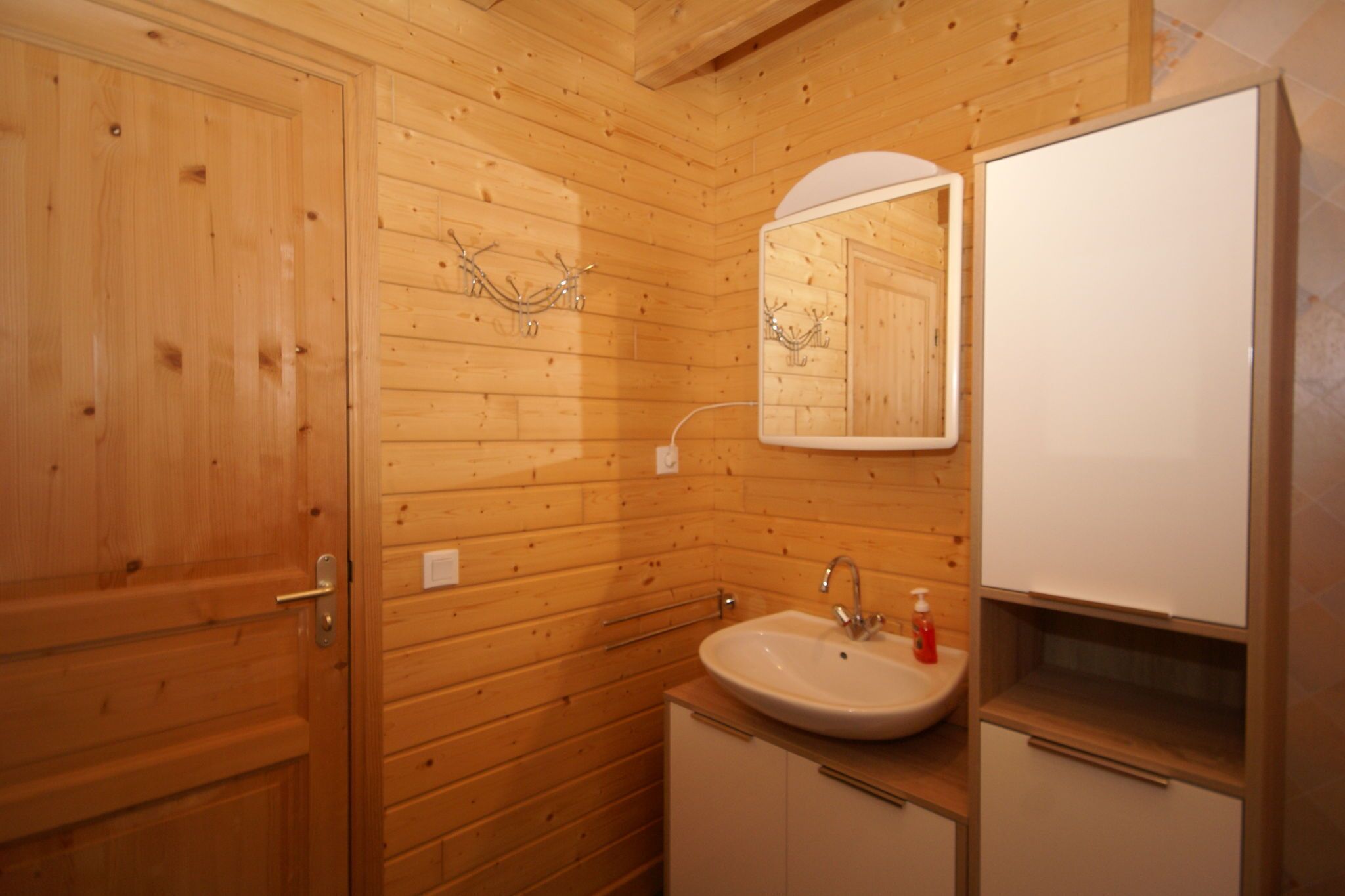 A wooden-paneled bathroom with a sink, mirror, and cabinets.