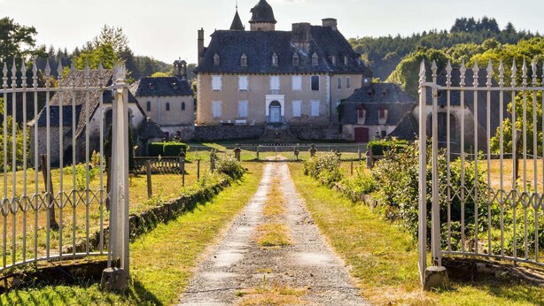 A historic building with a central entrance, surrounded by a gravel pathway and a metal gate. - Sénezergues Garden Hideaway (Sénezergues)