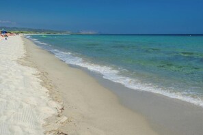 A beach with clear turquoise water, sandy shore, and distant hills. - Holiday resort, Budoni (Budoni)
