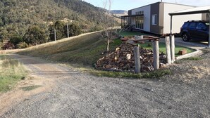 A modern house with a covered patio, a gravel driveway, and a car parked in the driveway. - Omeo Mountain Views. Peace and Tranquillity (Omeo)