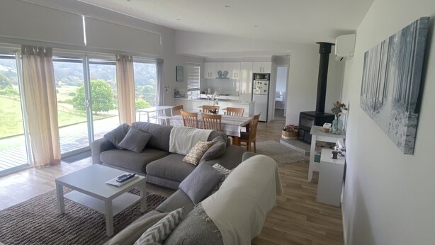 A modern living room with a sofa set, a coffee table, and a dining area with a table and chairs. - Omeo Mountain Views. Peace and Tranquillity (Omeo)