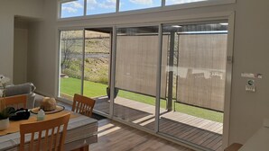 A room with a sliding glass door leading to a patio with a wooden deck and a grassy area. - Omeo Mountain Views. Peace and Tranquillity (Omeo)