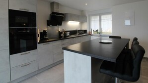 A modern kitchen with a central island, built-in appliances, and a large window providing natural light. - Renovated family house with sea view and terrace in Digosville (Digosville)