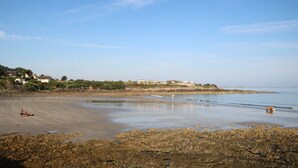 A coastal beach with rocky shorelines and buildings in the background. - Renovated family house with sea view and terrace in Digosville (Digosville)