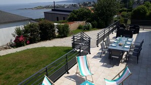 A terrace with a table set for dining, outdoor seating, and a view of the sea. - Renovated family house with sea view and terrace in Digosville (Digosville)