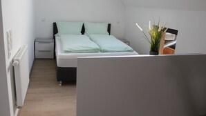 A bedroom with a bed, a nightstand, a radiator, and a skylight.