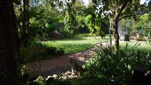 Um jardim com um caminho pavimentado, uma estátua e uma cerca de madeira.