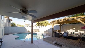 Un espace extérieur abrité comprenant une piscine, des sièges et un ventilateur de plafond.