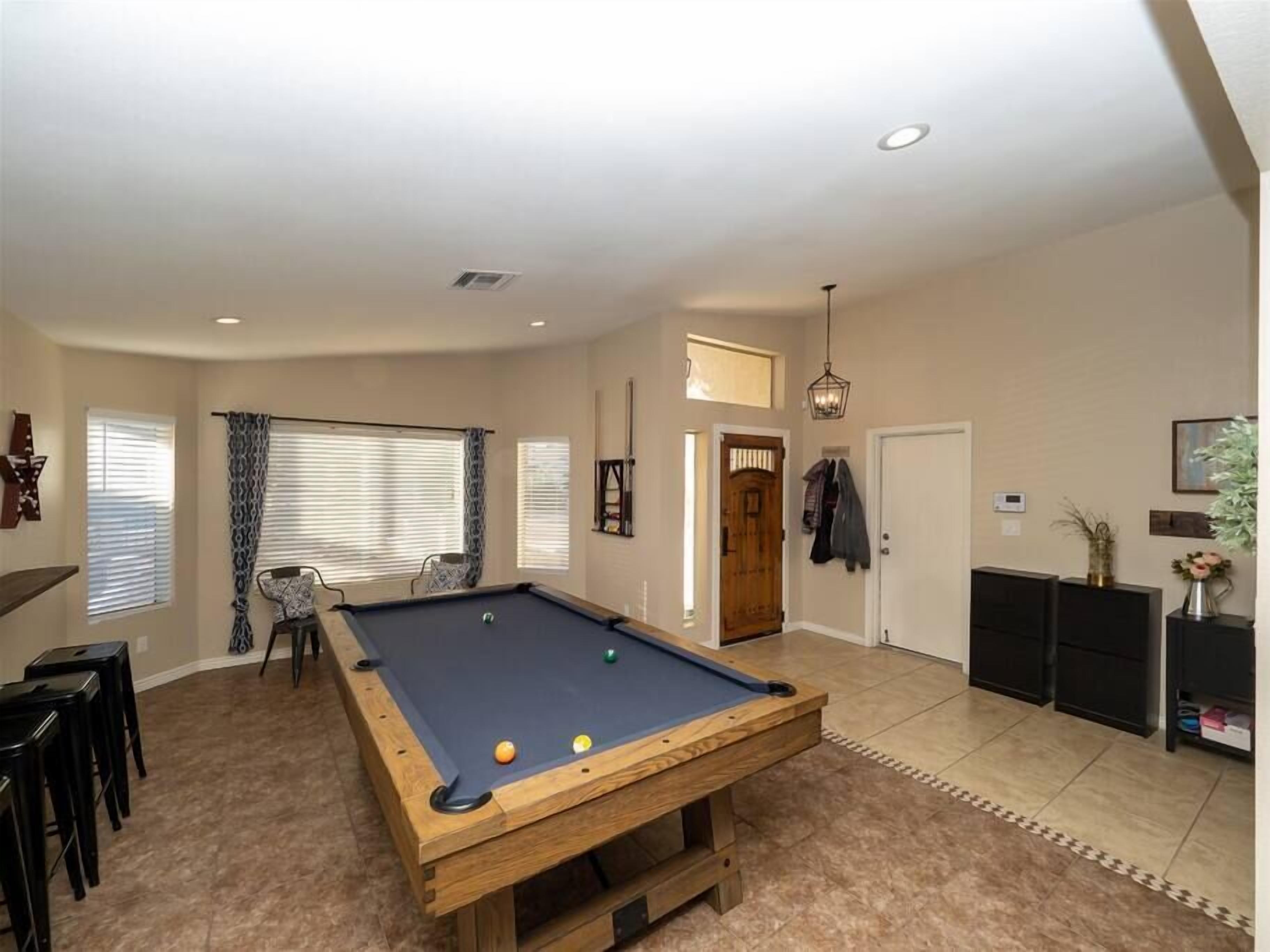 Une table de billard dans une pièce dotée d’une porte, d’un petit coin salon et d’un meuble.