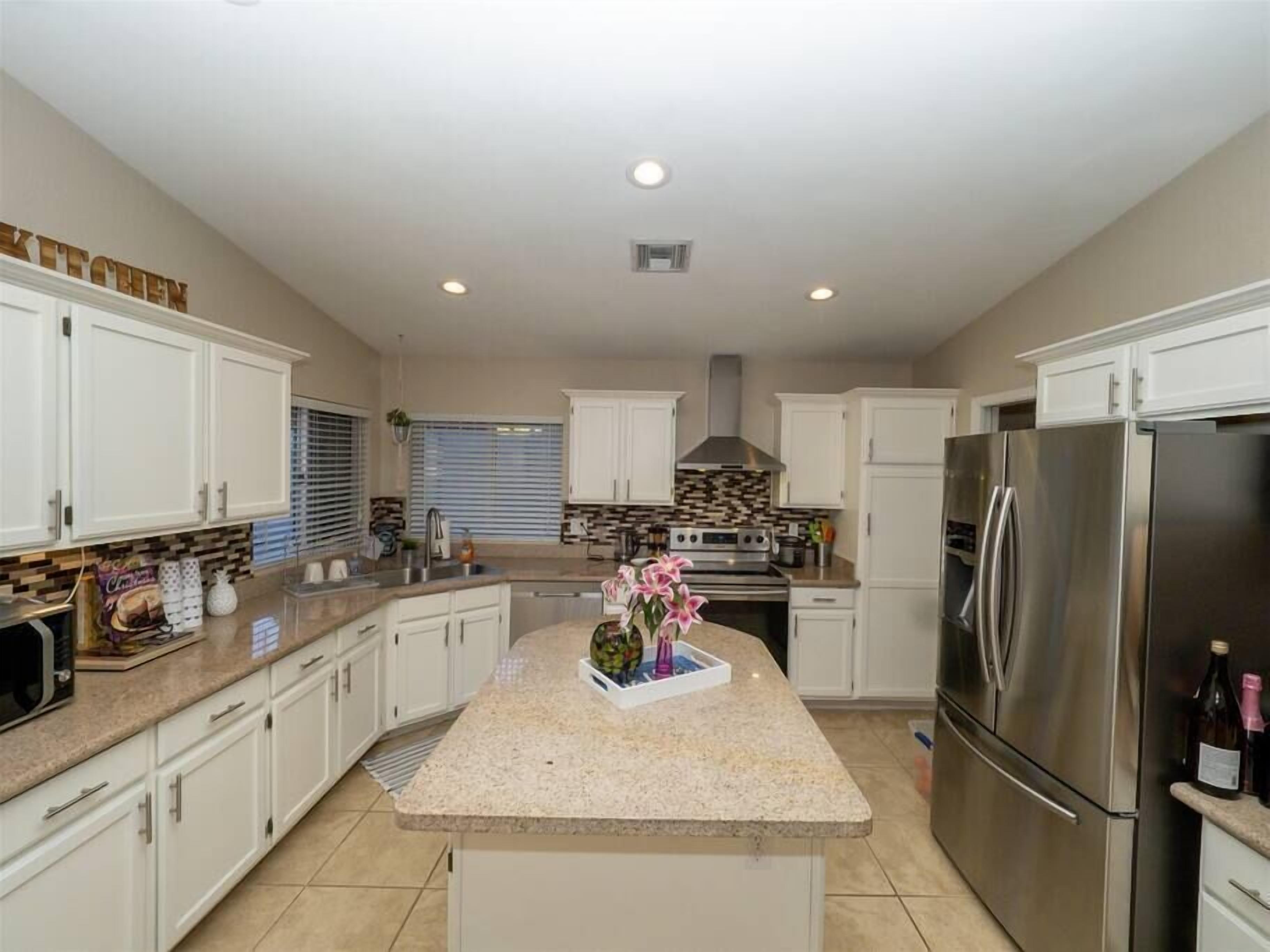 A kitchen with white cabinets, a central island, stainless steel appliances, and a backsplash.