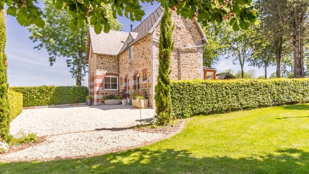 A stone building with a gravel driveway and a well-maintained lawn. - Charming stone house in Villedieu with garden (Villedieu-les-Poêles)