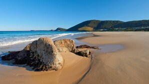 A beach with large rocks in the foreground and a clear view of the ocean. - Huey's Lookout - beachfront spacious pet friendly home (Blueys Beach)