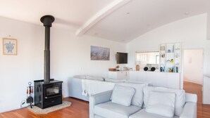 A modern living room with a fireplace, a sofa, a TV, and a kitchen area. - Huey's Lookout - beachfront spacious pet friendly home (Blueys Beach)