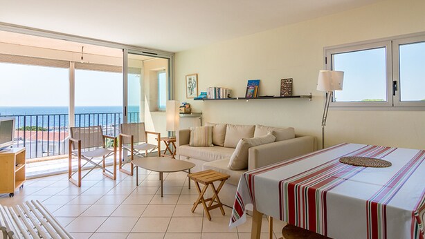Un vaste espace de vie comprenant un balcon, une table à manger et un canapé.