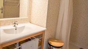 Une salle de bain avec un lavabo blanc, un miroir, un porte-serviettes et un rideau de douche.
