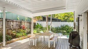 A covered patio with a wooden deck, a table, and chairs.