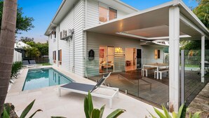A modern house with a swimming pool, a covered patio, and a glass door leading to an interior space.