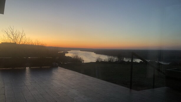 Une terrasse offrant une vue sur une rivière au coucher du soleil.