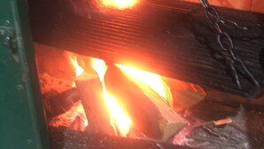 A fireplace with burning logs and a metal grate.