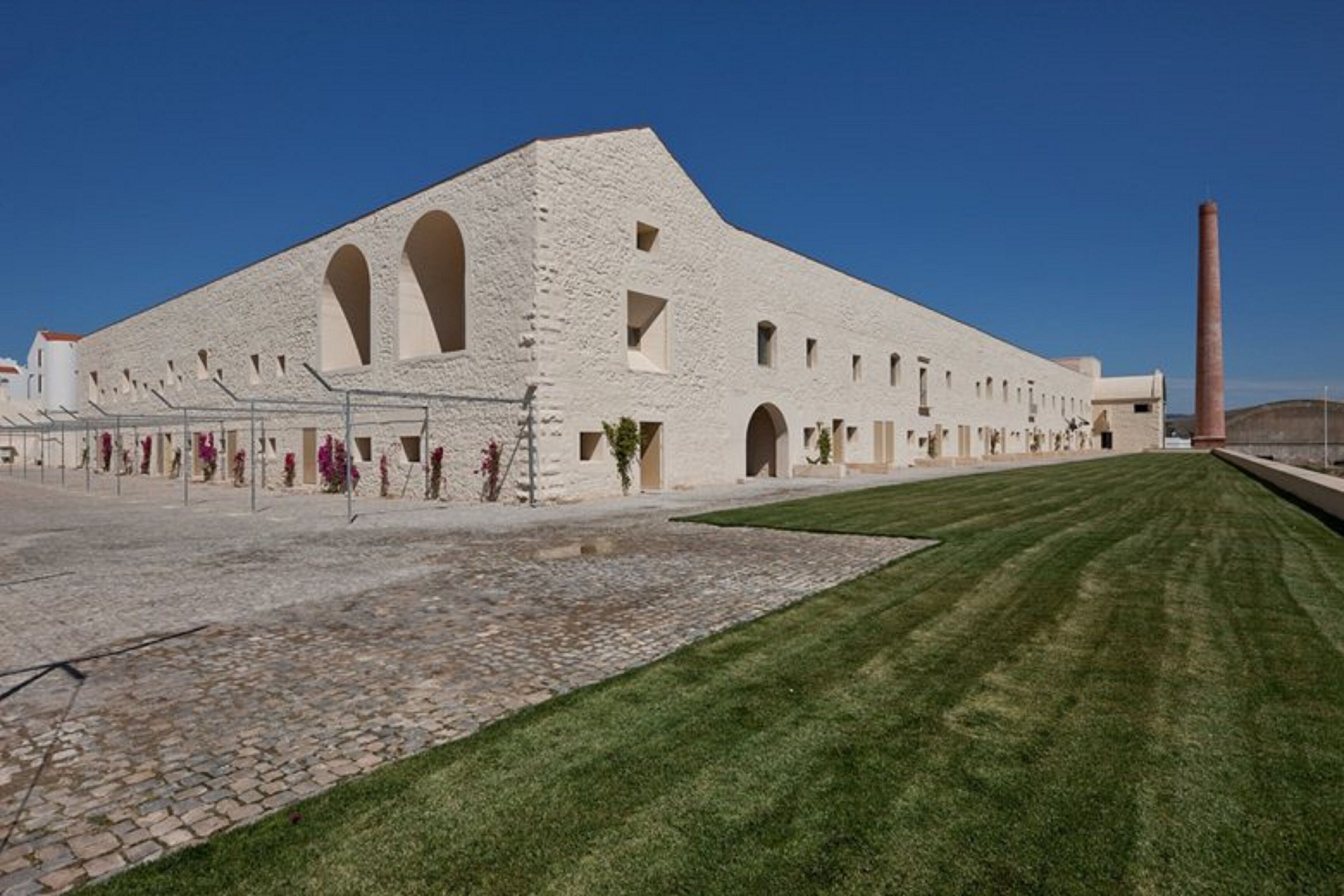Un edificio grande y blanco con múltiples ventanales arqueados y una torre central.