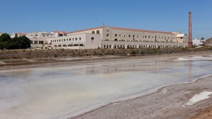A large industrial building with a long, narrow structure and a tall chimney.