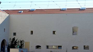 A poolside area with two wooden lounge chairs and a building with a tiled roof and small windows.