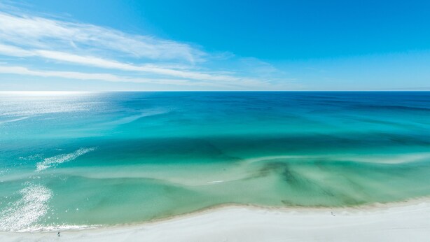 A beach with clear turquoise waters and a sandy shore.