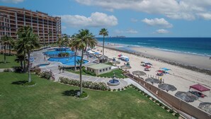 Een resort met een groot zwembadgedeelte, toegang tot het strand en uitzicht op de oceaan.