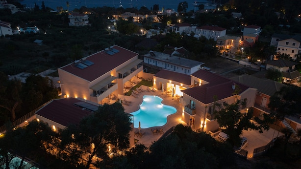 Un edificio grande con piscina rodeada de sillones de descanso y un patio cubierto.