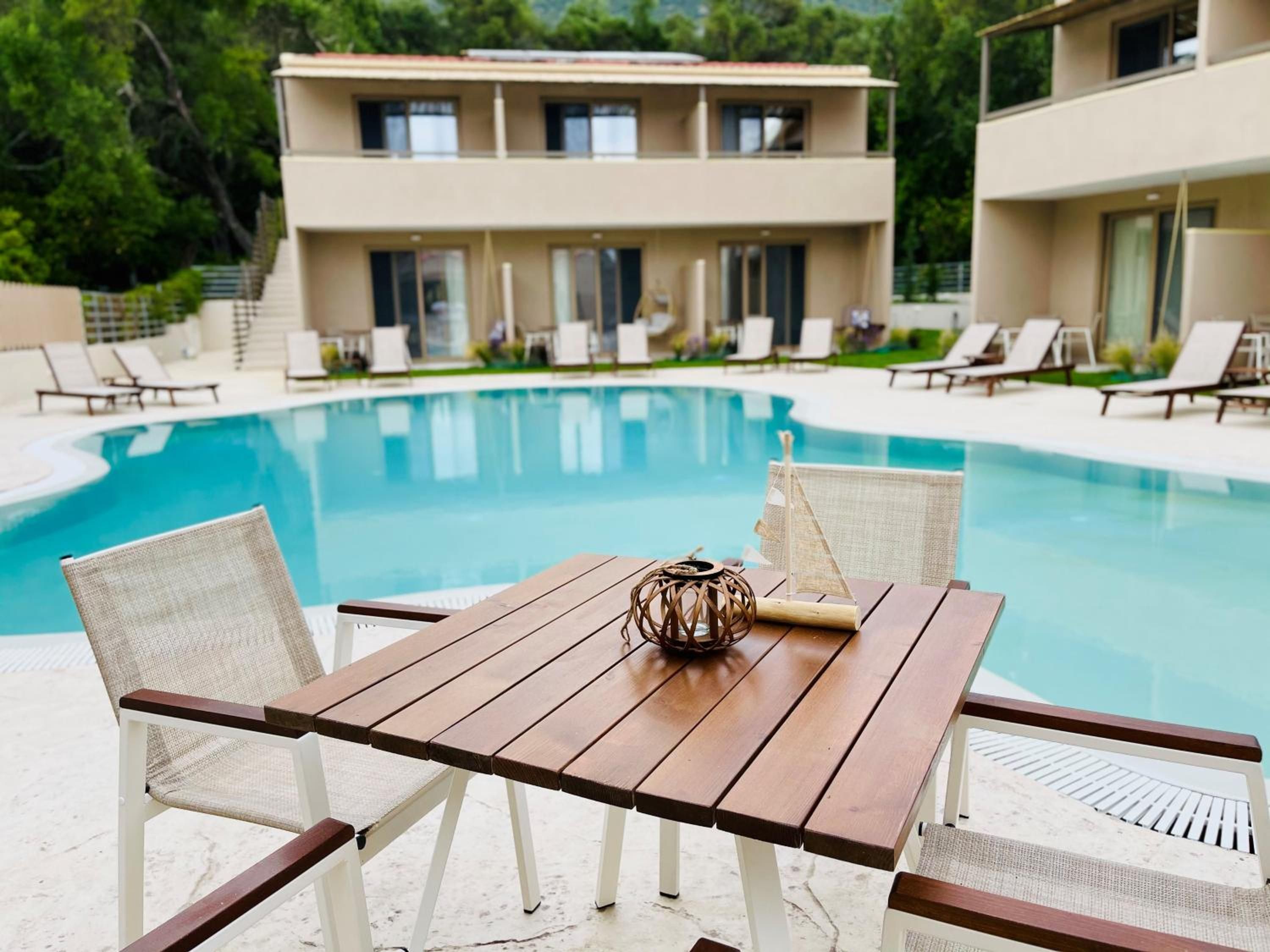 A poolside table with two chairs, a decorative item, and a building with multiple windows in the background.