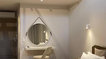 A modern bedroom with a bed, a desk, a chair, a round mirror, and a small balcony.