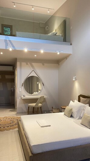 A modern bedroom with a bed, a desk, a chair, a round mirror, and a small balcony. - Scarabeo Suites & Villas (Parga)