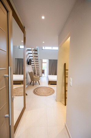 A modern interior with a staircase leading to a bedroom, a chair, and a bed. - Scarabeo Suites & Villas (Parga)