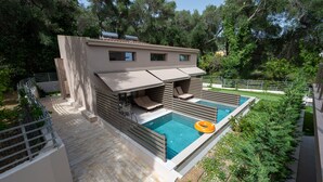 Una casa moderna con piscina, mobiliario exterior y jardín.