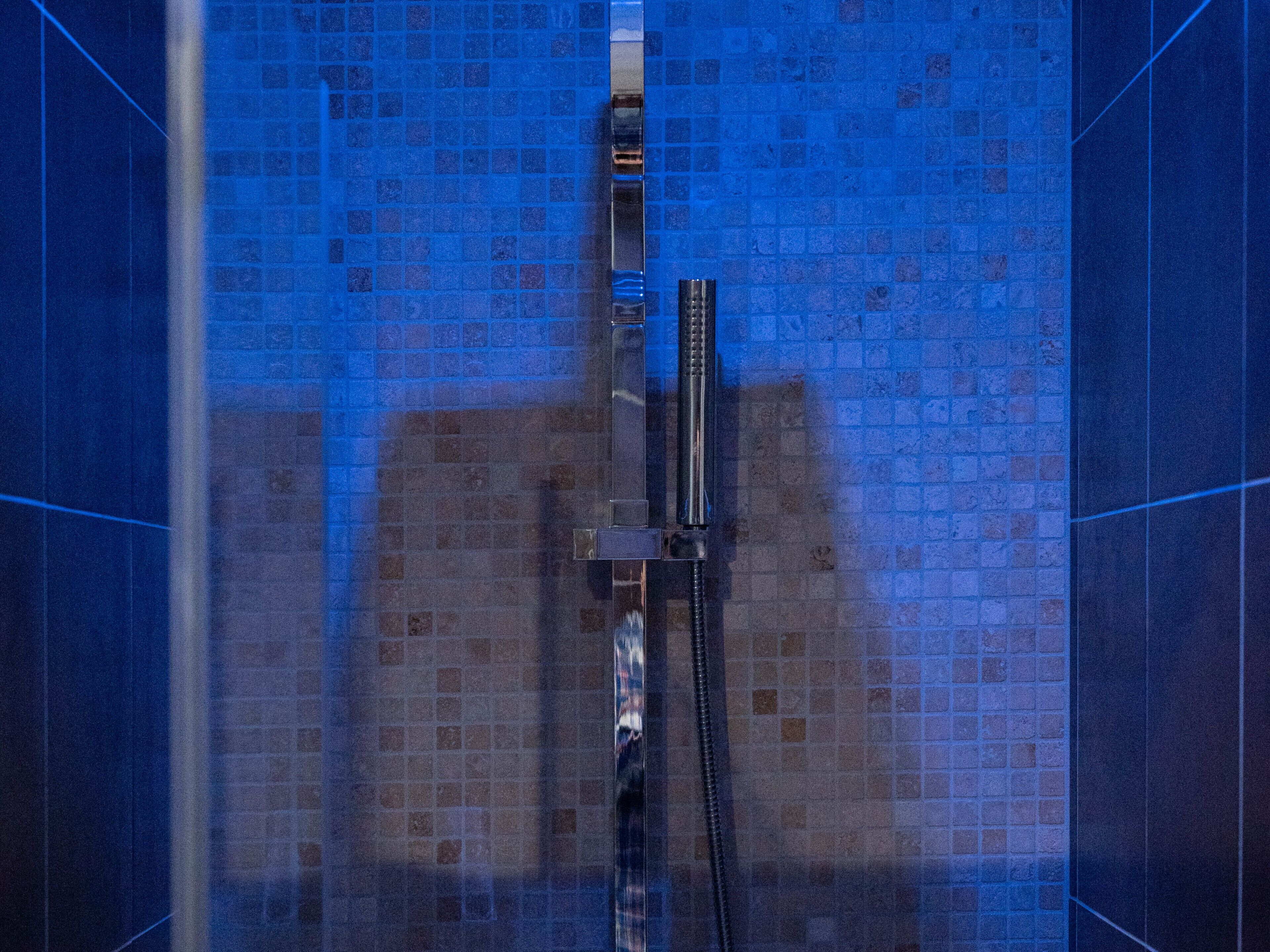 Een douche met betegelde wand en een handdouche.