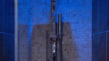 Een douche met betegelde wand en een handdouche.