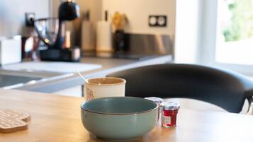 Une cuisine avec une table en bois, un bol, une tasse et un pot de confiture.