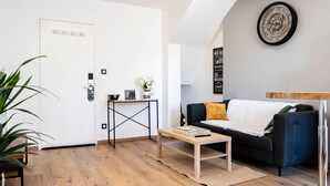 Una sala de estar moderna con piso de madera, un sofá azul oscuro, una mesa de centro y un reloj de pared.