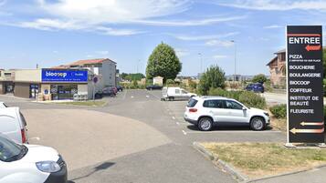 A parking lot with cars and a sign indicating directions to various local businesses.