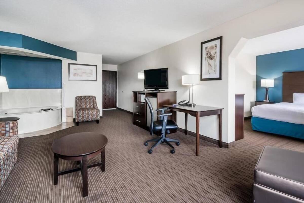 Ein Hotelzimmer mit Bett, Schreibtisch, Stuhl, Fernseher und einem kleinen Tisch.