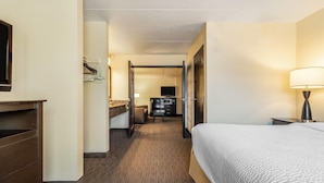 A hotel room with a bed, a desk, a chair, a TV, and a lamp. - Baymont By Wyndham Bloomington Msp Airport (Richfield)